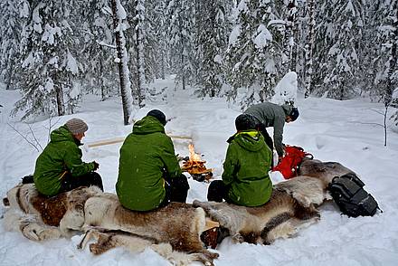 Menschen sind rund um ein Lagerfeuer im Schnee in Schweden