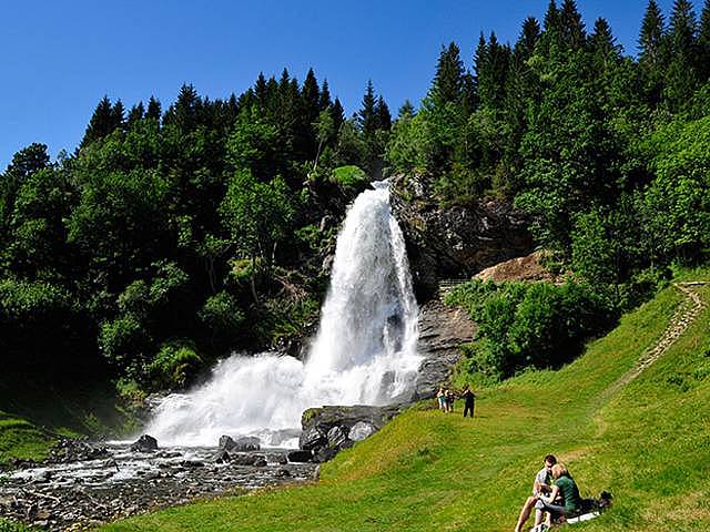 Leute auf einer Wiese vor einem Wasserfall in Norwegen