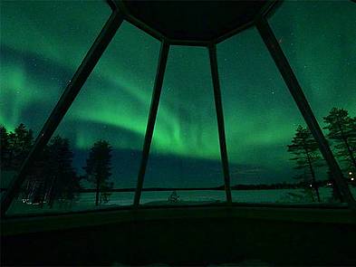 Polarlichter über dem Bett einer Skycabin in Finnland