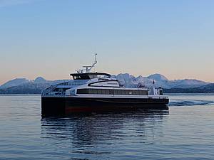 Ein Katamaran läuft im Winter in den Hafen von Harstad ein