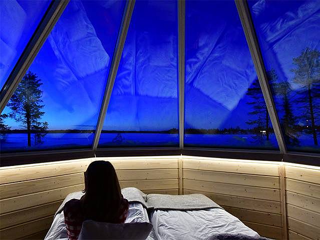 Eine Frau sitzt im Bett in einer Skycabin in Finnland